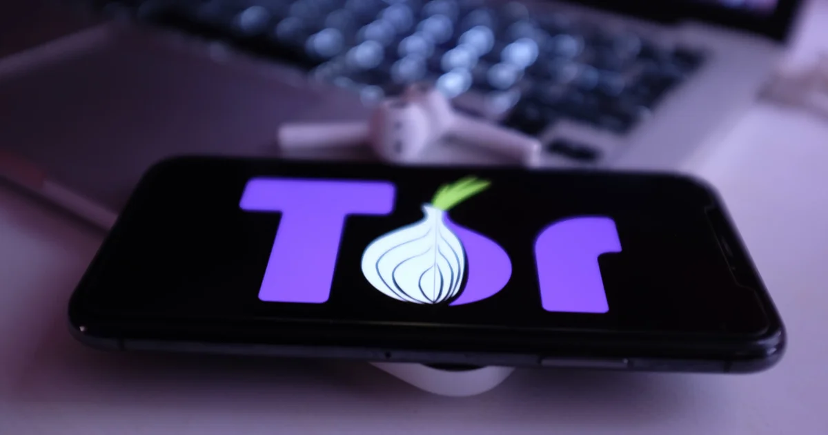 Tor Browser logo displayed on a smartphone screen, resting on a laptop.